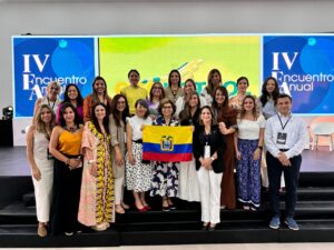 Group of women posing at an event and one is holding the flag of Ecuador
